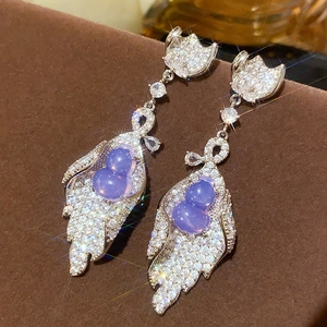 Macro shot of silver bow pearl earrings featuring purple stones and shimmering zircons
