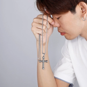 Dettaglio della collana con ciondolo a croce vintage a righe indossata da un uomo