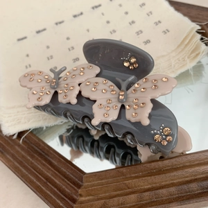 Close-up of grey acetate hair claw clip with pink butterflies and champagne rhinestones