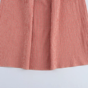 Close-up of red and white plaid fabric texture with natural drape and stitch details