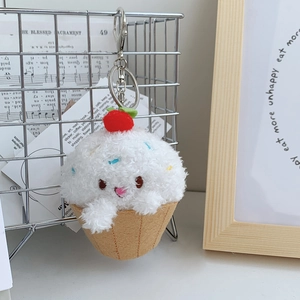 Close-up of strawberry cream dessert plush pendant on a metal grid with music sheets