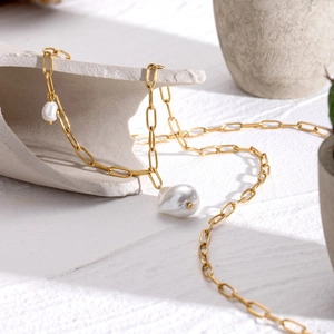 Detail of 18k gold plated chain with asymmetric baroque pearls on white stone