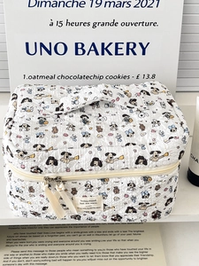 Close-up of quilted cosmetic bag featuring dog prints and cream ribbon zipper pull
