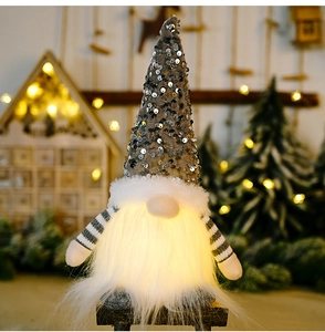 Close-up of glowing Christmas gnome with grey sequin hat and warm LED lights