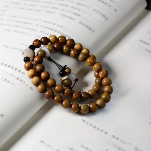 Detailed macro view of sandalwood multi-layer bracelet with lotus beads on vintage book