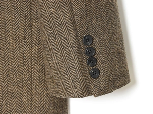 Detail of brown herringbone wool blazer cuff featuring four classic black round buttons