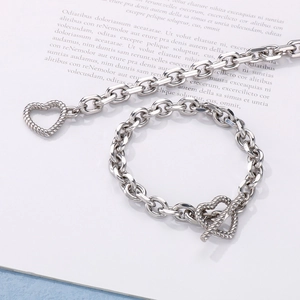 Detail of silver chain bracelet with textured heart toggle clasp on a white book