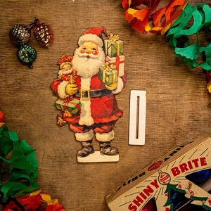 Close-up of vintage cardboard Santa Claus decoration with wooden base on tabletop