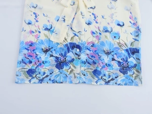 Dettaglio camicetta in chiffon a fiori con fiocco sul collo e bottoni bianchi