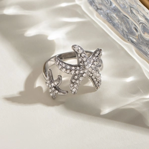 Silver starfish ring with sparkling crystals on a textured glass display background