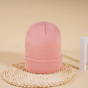 Close-up of pink knit beanie showing detailed texture and ribbed cuff on neutral background
