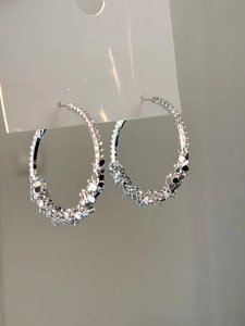 Macro shot of silver hoop earrings featuring irregular faceted metallic textures