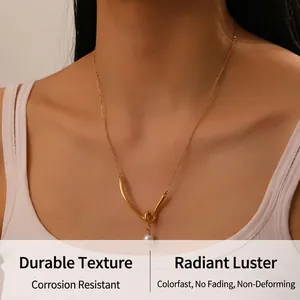 Detail of twisted V-pendant gold necklace with white pearl on model neck
