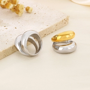 Close-up of polished silver and gold stacked rings on a natural stone surface