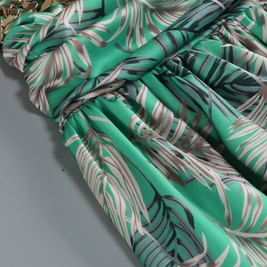 Detail of green palm leaf print pleated fabric with a luxury gold metal chain strap