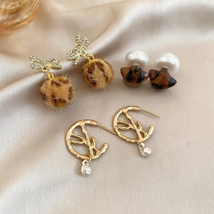 Detail of leopard print earrings set featuring pearls, rhinestones and silk background