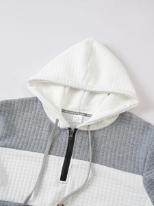 Detail of color-block quilted hoodie showing neckline label, zipper and gray drawstring