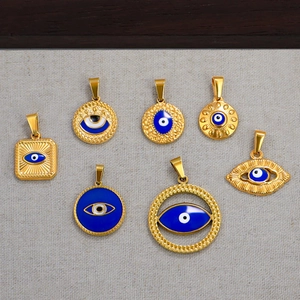 Detail view of seven assorted 24k gold plated evil eye pendants on grey fabric background