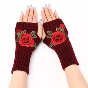 Close-up of wine red knitted fingerless gloves with elegant rose embroidery detail