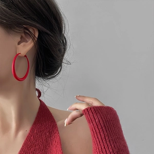 Minimalist red matte hoop earrings worn by a model in a stylish side profile shot