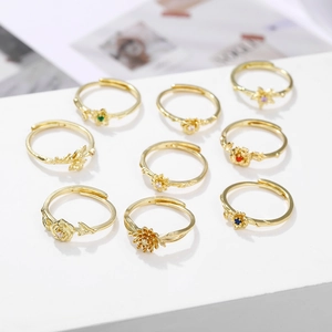 Detailed display of nine gold-plated adjustable floral rings with colored zircon stones