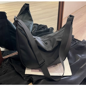 Detail of black nylon dumpling crossbody bag showing large capacity and smooth texture