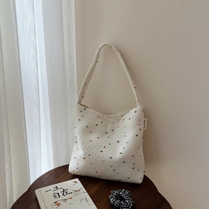 Borsa tote intrecciata bianca minimalista con macchie colorate su un tavolo di legno