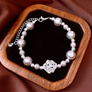 Close-up of pearl bracelet with zircon flower pendant in a velvet wooden tray