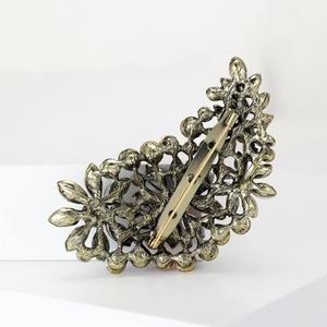 Vintage gold hollow leaf brooch with intricate retro pattern on a white background