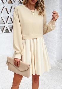 Détail d'une robe beige style deux pièces avec jupe plissée et corsage à manches longues