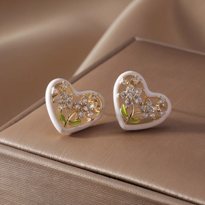 Gold heart earrings with white enamel and green zircon accents on silk jewelry box