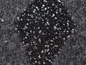 Detalle macro de tejido de punto gris oscuro con lentejuelas brillantes y textura