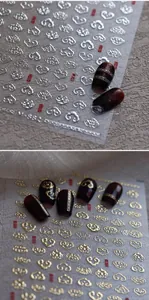 Macro detail of gold and silver Chinese cloud nail stickers on deep red glossy nails