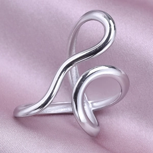 Macro shot of silver-colored curved metal ring on elegant pink silk background