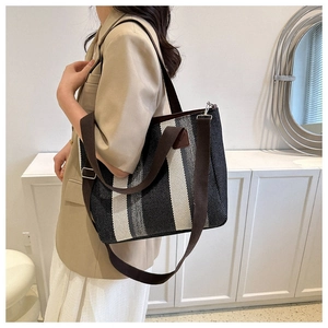 Detail of striped canvas tote showing woven texture, brown straps and zip closure