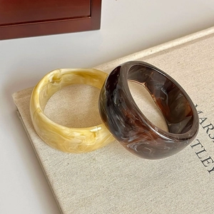 Detailed shot of amber and tortoise resin bangles with marble texture on linen fabric