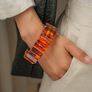 Detail shot of vintage amber acrylic bangle with scalloped edges worn by a model