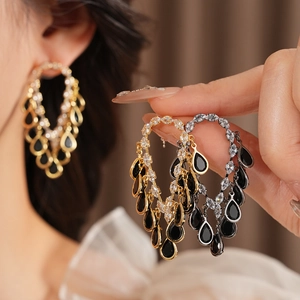 Macro shot of sparkling zircon teardrop tassel earrings in gold and dark metal finishes