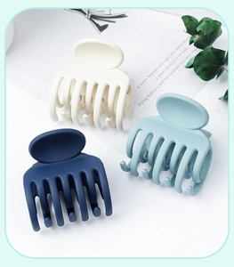 Close-up of three matte hair claws in cream, navy, and light blue on a clean background