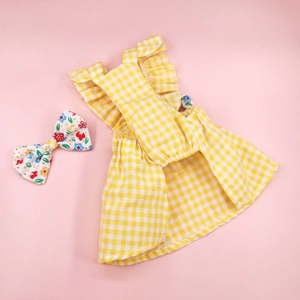 Detail of yellow plaid pet dress with ruffle edges and matching floral bow accessory
