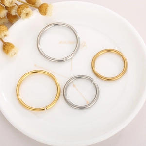 Polished stainless steel open jump rings in gold and silver colors on white tray