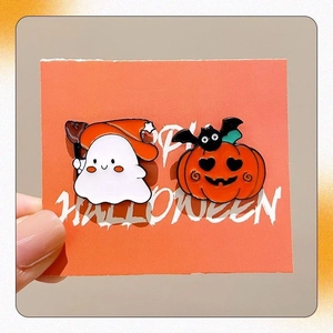 Detail shot of Halloween enamel pins featuring a cute ghost and pumpkin on an orange card