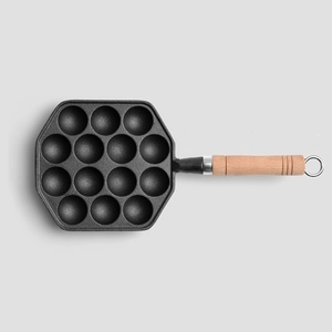 Padella per takoyaki in ghisa con 14 fori e manico in legno su sfondo grigio