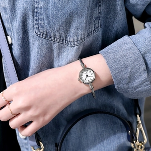Silver cuff watch with white round dial and Roman numerals worn on female wrist