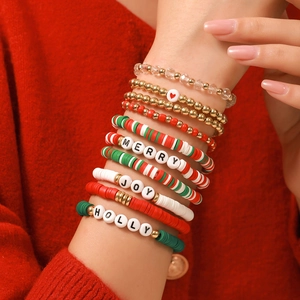 Gros plan de perles en argile rouge et vert et de bracelets dorés de Noël