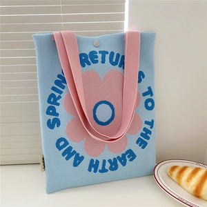 Detail of blue knitted tote bag featuring pink floral patterns and soft woven texture
