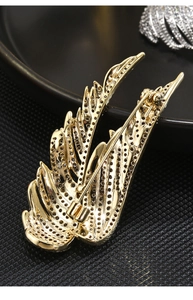 Macro view of luxurious golden wing brooch with zircon crystals on a black background