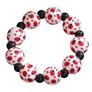 Vue détaillée du bracelet avec motifs de coccinelles et de cœurs sur des perles blanches
