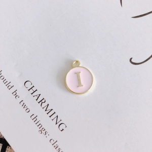 Detail of pink enamel round pendant with gold letter I for DIY jewelry making