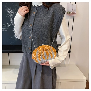 Detailed view of rhinestone pumpkin evening bag held by a model in a stylish outfit